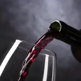 Vin rouge versé d'une bouteille dans un verre. Le moment idéal pour estimer un vin avant de le déguster.
