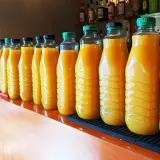 Une longue rangée de bouteilles de jus d'orange, prêtes pour une fête. 5 litres de punch pour combien de personnes ?