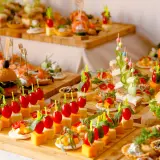 Un apéro dinatoire pour 10 personnes : mini-burgers, brochettes de tomates-mozzarella, tartines et verrines joliment dressés sur des planches en bois.