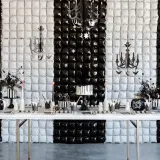 Table dressée pour une activité anniversaire mercredi Addams : gâteau, citrouille, décorations gothiques sur fond rayé noir et blanc.
