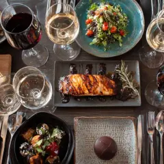 Un verre de pinot noir avec un plat de poisson grillé, accompagné de salades, fromages et desserts.
