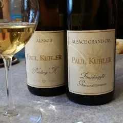 Verre de vin blanc alsacien, idéal pour accompagner une choucroute. Deux bouteilles Paul Kubler Riesling K et Gewurztraminer sont visibles.