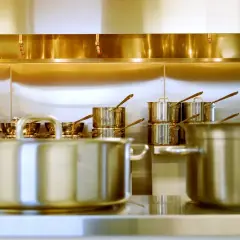 Une cuisine professionnelle avec des casseroles en inox 18/0 étincelantes sous une hotte aspirante.