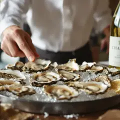 Un Chablis, le vin blanc parfait avec les huîtres de Marennes. Un serveur arrange un plateau d'huîtres fraîches sur de la glace, prêt à être dégusté.