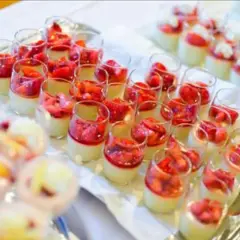 Plateau de mini dessert pour buffet : verrines crémeuses garnies de fraises fraîches et d'une touche de coulis rouge.
