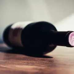 Une bouteille de vin couchée sur une table en bois. La question se pose : 1 bouteille de vin pour combien de personnes ?
