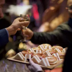 Deux hommes portent des verres et un plateau de mini-sandwichs et de bagels, prêts pour une boisson soirée.