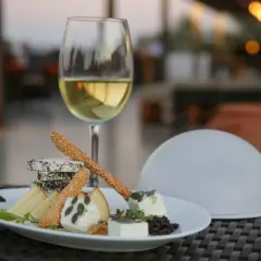 Un verre de vin blanc et une assiette de fromages variés, parfaits pour savoir que manger avec un gewurztraminer.