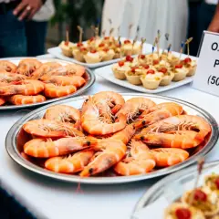 Plateaux de crevettes pour un buffet. Une pancarte indique "O.I Faterne Prapriitive (50 a 75 g)", suggérant combien de crevettes par personne.