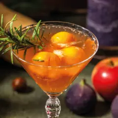 Cocktail fruité avec des pêches et du romarin, parfait pour une idée apéro mariage. Pomme et figues en arrière-plan.