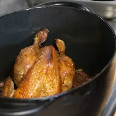Une poularde dorée mijote dans une cocotte. Quel vin avec une poularde ? Un blanc de Bourgogne ou un rouge léger serait parfait.