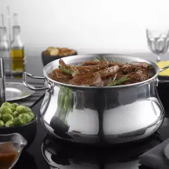 Un plat mijoté dans une cocotte en aluminium brillant, prêt pour le nettoyage. Des accompagnements comme des choux de Bruxelles et du riz sont disposés autour.