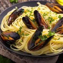 Un plat de spaghetti aux moules, parsemé de persil frais. Un accompagnement parfait pour des moules savoureuses.