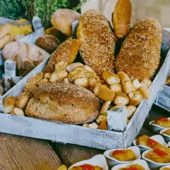 Plateau de pains variés, idéal pour organiser un petit déjeuner pour 30 personnes. Des miches rondes, des baguettes aux graines de sésame et des petits pains croustillants.