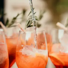Verre de boisson soft mariage rempli de glaçons et d'une tranche d'orange, garni de romarin.