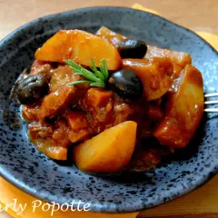 Un plat appétissant de sauté de veau à la tomate, garni d'olives noires et de romarin. Quel vin avec sauté de veau à la tomate ? Un rouge léger serait parfait.
