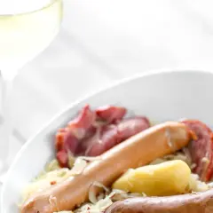Un verre de vin blanc accompagne une choucroute de la mer généreuse avec saucisses et pommes de terre. Quel vin avec choucroute de la mer ?
