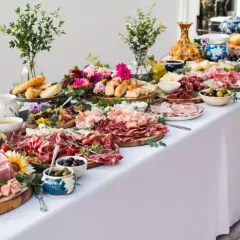 Un magnifique buffet restauration débordant de charcuteries, fromages, pains et olives, décoré de fleurs fraîches.