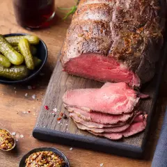 Un rôti de bœuf froid, tranché, prêt à servir pour 20 personnes, accompagné de cornichons et de moutarde à l'ancienne.