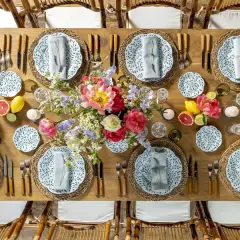 Table dressée pour un repas mariage champêtre, avec fleurs, fruits et vaisselle décorée de feuilles vertes.