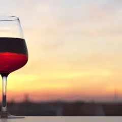 Verre de vin rouge bordeaux, parfait pour apprécier sa température idéale au coucher du soleil.