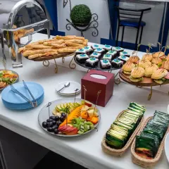 Un buffet de hors d'œuvre varié avec mini-burgers, pâtisseries, bâtonnets feuilletés et salade de fruits.