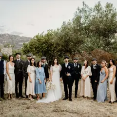Mariage Peaky Blinders : le couple et leurs témoins, tous habillés de costumes d'époque, posent devant un paysage rocheux et verdoyant.