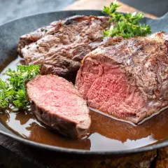 Un rôti de chevreuil juteux, coupé en tranches, baignant dans une sauce savoureuse. Un plat qui invite à se demander quel vin avec du chevreuil serait le meilleur accord.