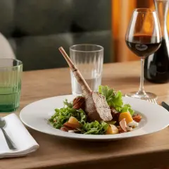 Un gigot d'agneau avec flageolets, servi avec un verre de vin rouge. Un plat parfait pour un repas savoureux.