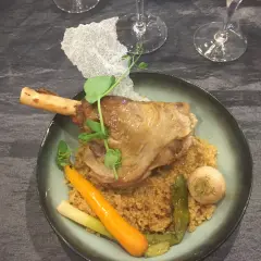 Souris d'agneau braisée au vin, servie sur un lit de couscous avec carottes et navet. Un plat savoureux et réconfortant.