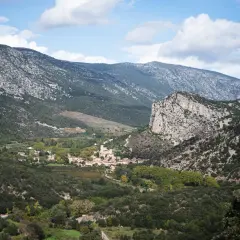 Vue panoramique sur le village de Saint-Guilhem-le-Désert, niché au creux de montagnes rocheuses. Un paysage idéal pour déguster un vin rouge local.
