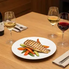 Un plat de bar grillé avec des légumes, accompagné d'un verre de vin rouge. Quel vin rouge avec du bar ? Ce plat invite à la dégustation.