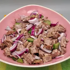 Salade de viandes froides, un plat savoureux avec des morceaux de viande, des oignons rouges et des avocats, servi dans un bol rose.