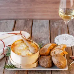 Un Mont d'Or au four, pommes de terre, pain et vin blanc. Quel vin avec Mont d'Or au four ? Un accord parfait pour un repas convivial.