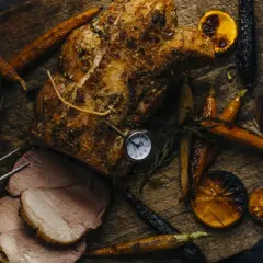 Un rôti de porc savoureux, accompagné de carottes rôties, d'oranges caramélisées et d'un verre de vin rouge. Parfait pour un repas d'automne.