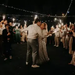Mariage intime pour 30 personnes : le couple s'embrasse sous les feux de la rampe, entouré de ses proches.