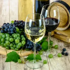 Deux verres de vin, rouge et blanc, accompagnés de grappes de raisins et d'un fût de chêne. Un millésime haut Médoc promet une dégustation exquise.