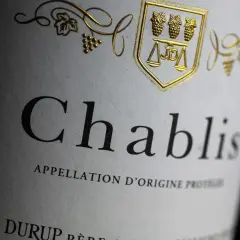 Gros plan sur l'étiquette d'une bouteille de Chablis, avec un blason doré. La conservation de ce vin est essentielle pour apprécier sa finesse.
