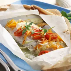 Un plat de cabillaud en papillote, garni de tomates cerises et d'herbes. Un délice pour savoir quel vin avec du cabillaud.
