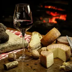 Verre de vin rouge, truffes noires, fromages et pain sur une table en bois, près d'une cheminée. Un délice pour accompagner un vin avec truffade.