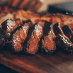 Tranches de viande grillée sur une planche en bois. Idéal pour savoir quel vin avec une pierrade.