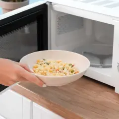 Une main place un bol de riz aux légumes dans un micro-ondes. Ce bol en mélamine est parfait pour réchauffer vos plats au micro-onde.