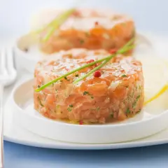 Deux tartares de saumon frais, garnis de ciboulette et de poivre rose, prêts à être dégustés. Parfait pour savoir que boire avec un tartare de saumon.