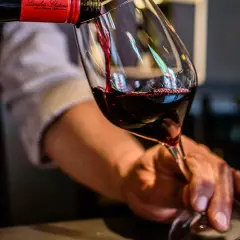 Service d'un vin rouge, idéalement servi à la bonne **température Saumur Champigny**. Le vin est versé dans un verre, avec une autre verre déjà rempli.