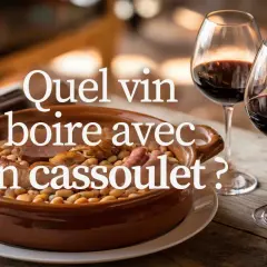 Un plat de cassoulet fumant, deux verres de vin rouge et une bouteille. La question se pose : quel vin boire avec un cassoulet ?