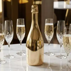 Une bouteille dorée de crémant entourée de verres pétillants. Combien de verre dans une bouteille de crémant ? 7 verres sont prêts à être remplis.