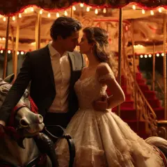 Un couple s'embrasse sur un manège de cirque illuminé, une scène romantique pour un mariage de rêve.