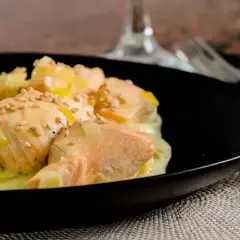 Délicieuse blanquette de saumon au vin blanc, parsemée de graines de sésame, servie dans une assiette noire.