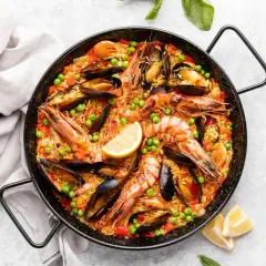Paella royale aux crevettes et moules, garnie de pois et de citron. Quel vin avec la paella royale ? Un vin blanc sec et fruité, ou un rosé léger.