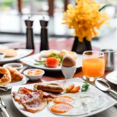 Un copieux petit déjeuner continental ou américain avec œufs, bacon, saucisses, viennoiseries, jus d'orange et café.